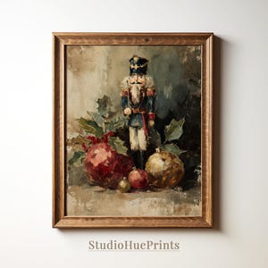 Puede incluir: Pintura enmarcada de estilo vintage con un cascanueces, adornos navideños y acebo. El cascanueces viste un uniforme azul y rojo. Los adornos son rojos y dorados. La pintura tiene una paleta de colores cálidos y neutros y el texto "StudioHuePrints".