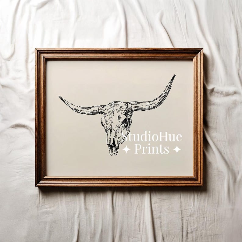 K&ouml;nnte beinhalten: Ein gerahmter Druck mit einer schwarz-wei&szlig;en Illustration eines Longhorn-Sch&auml;dels. Das Kunstwerk ist vor einem neutralen Hintergrund platziert und in dunklem Holz gerahmt. Der Text "studioHue Prints" ist sichtbar.