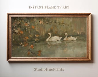May include: A framed painting of two white swans swimming in a pond with green foliage and orange leaves in the background. The painting is in a brown wooden frame.
