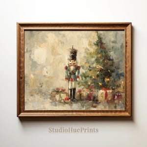 Könnte beinhalten: Ein Ölgemälde in einem braunen Holzrahmen, das einen Nussknacker neben einem geschmückten Weihnachtsbaum mit verpackten Geschenken am Fuß zeigt. Das Kunstwerk weist eine gedämpfte Farbpalette mit sichtbaren Pinselstrichen und den Text StudioHuePrints auf.