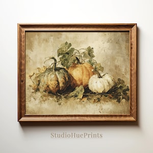 May include: A framed print featuring a still life of pumpkins. The artwork showcases three pumpkins in shades of orange, white, and green, surrounded by green leaves. The print has a vintage aesthetic and is set in a brown wooden frame.