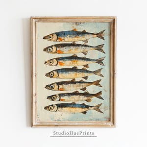 Puede incluir: Una impresión enmarcada de una ilustración vintage de ocho peces plateados sobre un fondo azul claro. Los peces están dispuestos en una fila vertical, con las colas apuntando hacia la derecha. El marco es de madera clara.