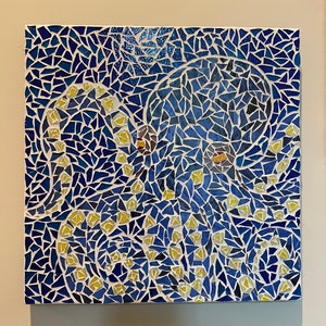 May include: Square mosaic art piece featuring an octopus design. The artwork uses blue, white, and yellow tiles to create the image. The octopus has yellow suckers and brown eyes, set against a blue background.