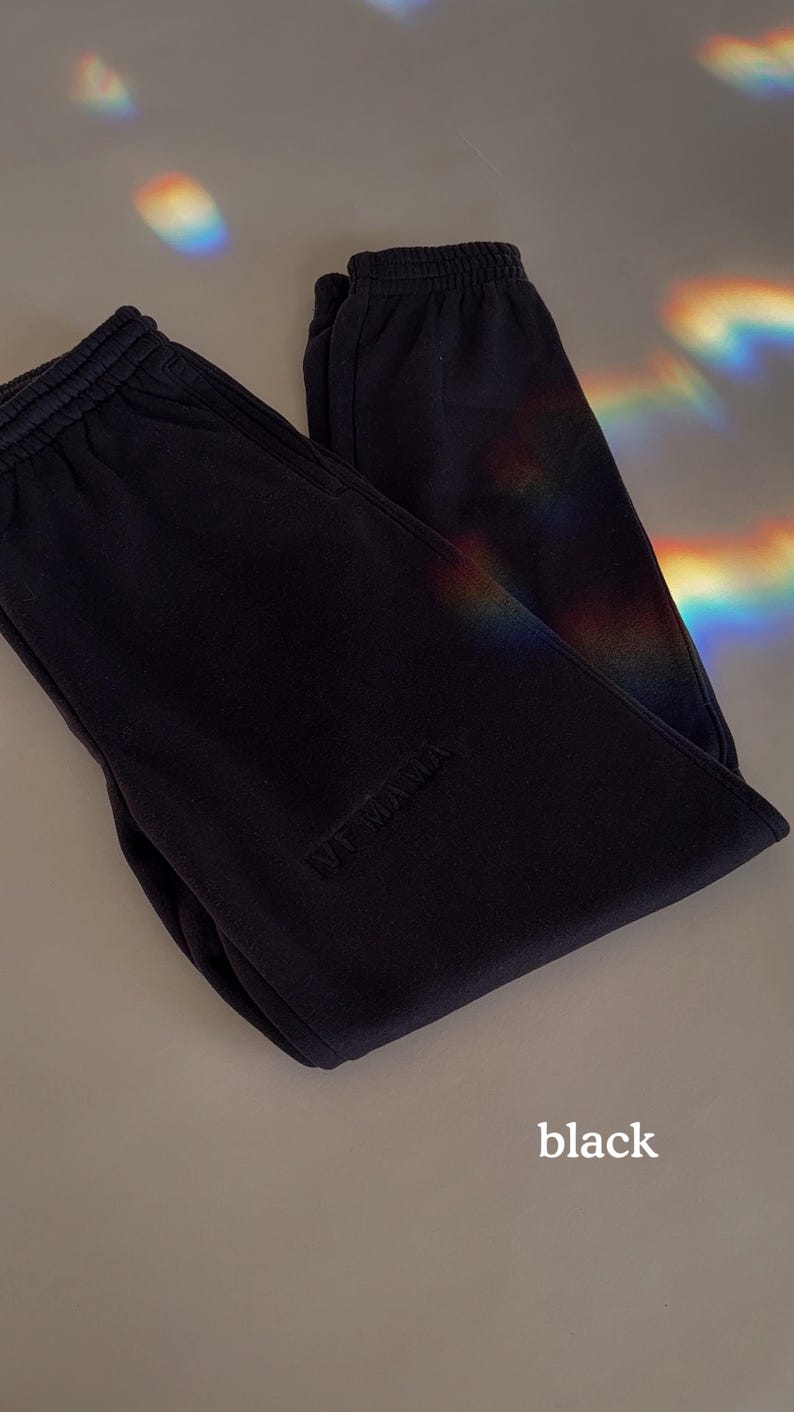 Puede incluir: Pantalones de ch&aacute;ndal negros con un logotipo "NY" blanco bordado en la pierna izquierda.