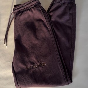 Puede incluir: Pantalones de ch&aacute;ndal de color marr&oacute;n oscuro con cintura el&aacute;stica y el texto "IVF MAMA" bordado en la pierna izquierda.