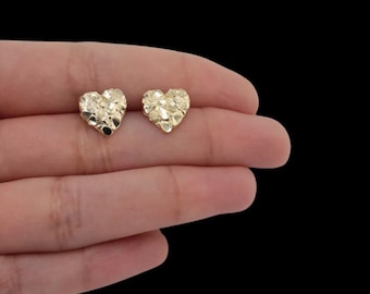 May include: A pair of gold heart-shaped earrings with a textured finish.