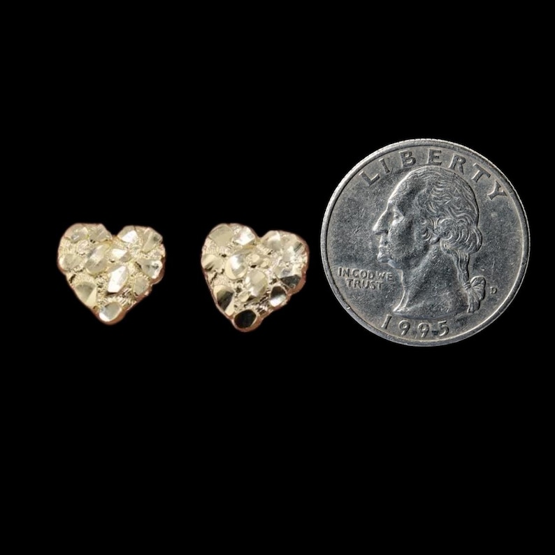 May include: Two gold heart-shaped earrings with a textured surface. The earrings are shown next to a US quarter for size comparison.