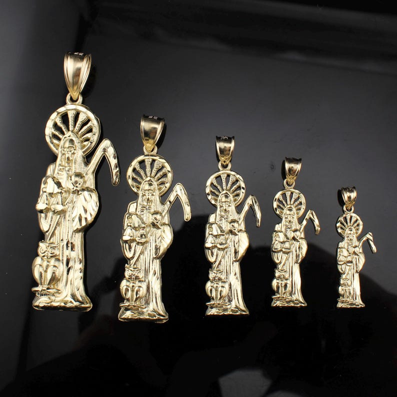 May include: A collection of gold-colored pendants featuring a religious figure with a halo, holding a scythe. The pendants vary in size, with intricate details in the design. The background is a dark, reflective surface.