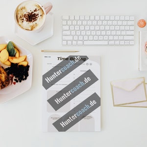 Könnte beinhalten: Ein weißer, druckbarer Zeitblock-Planer mit dem dreimal wiederholten Text "Huntercoach.de". Der Planer liegt auf einer weißen Oberfläche mit einer Tasse Kaffee, einem Teller mit Obst und Gebäck, einer Tastatur und Briefumschlägen.