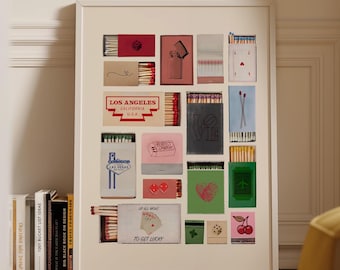 May include: A framed print featuring a collection of colorful matchbox designs. The print includes various rectangular matchbox illustrations with text and graphics, including "LOS ANGELES" and "TO GET LUCKY". The artwork is displayed on a wooden floor.