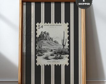 May include: Framed print featuring a vintage 5-cent United States postage stamp design. The stamp depicts a desert landscape with cacti and mountains. The background is black and white striped. The frame is made of wood.