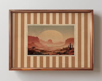 May include: A framed print of a desert landscape with a large, orange sun in the sky. The print is set against a background of brown and beige vertical stripes.