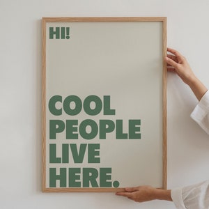 Op de afbeelding: Een ingelijst print met een lichtgroene achtergrond en de tekst "HI! COOL PEOPLE LIVE HERE." in donkergroene letters.