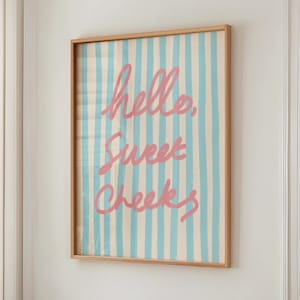 Puede incluir: Una impresión enmarcada con un fondo a rayas azul y blanco y el texto "hello, sweet cheeks" en rosa.