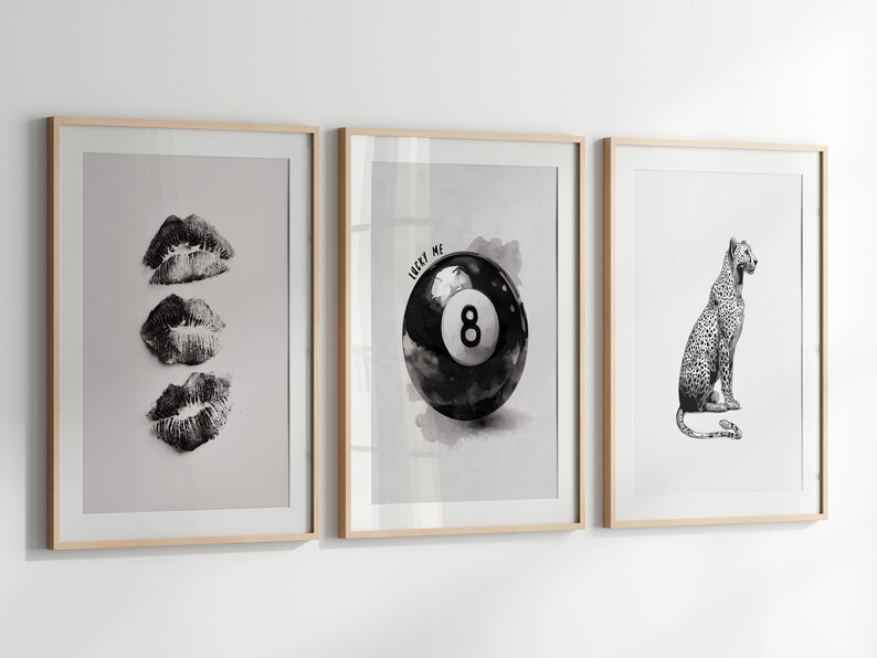 May include: Three framed black and white prints. The first features three lip prints. The second shows a black eight ball with the text "LUCKY ME". The third depicts a leopard. All are in light wood frames.
