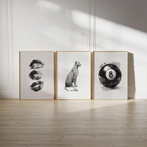 May include: Three framed art prints with gold frames. The left print features three black and white lip prints. The center print shows a leopard. The right print displays a black and white 8-ball with the text "LUCKY ME".