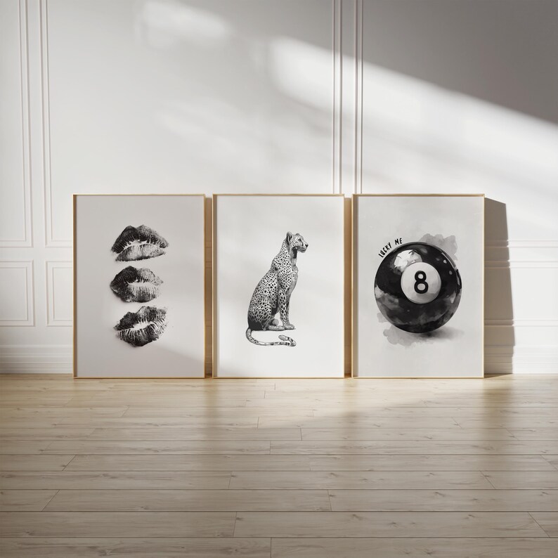 May include: Three framed art prints with gold frames. The left print features three black and white lip prints. The center print shows a leopard. The right print displays a black and white 8-ball with the text "LUCKY ME".
