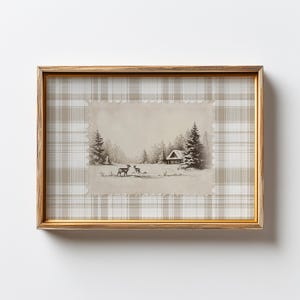 以下が含まれることがあります： 冬の風景を描いた額入りのアートプリント。雪原にいる鹿の白黒イラストで、背景には小屋と木々が描かれています。フレームは金色で、背景はベージュと白のチェック柄です。