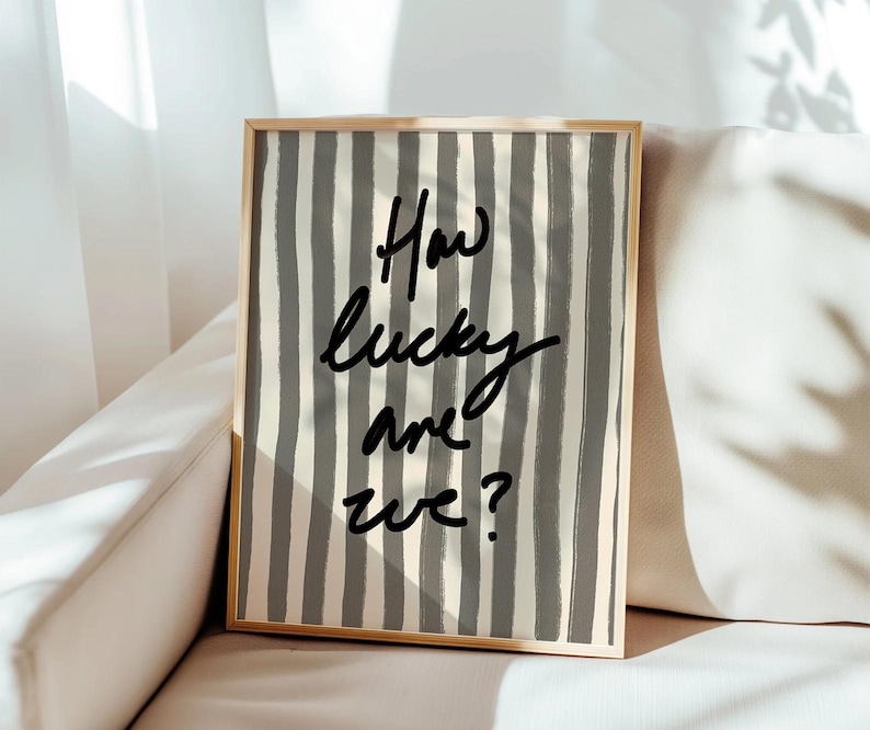 May include: A framed print with a grey and white striped background and the text "How lucky are we?" in black.