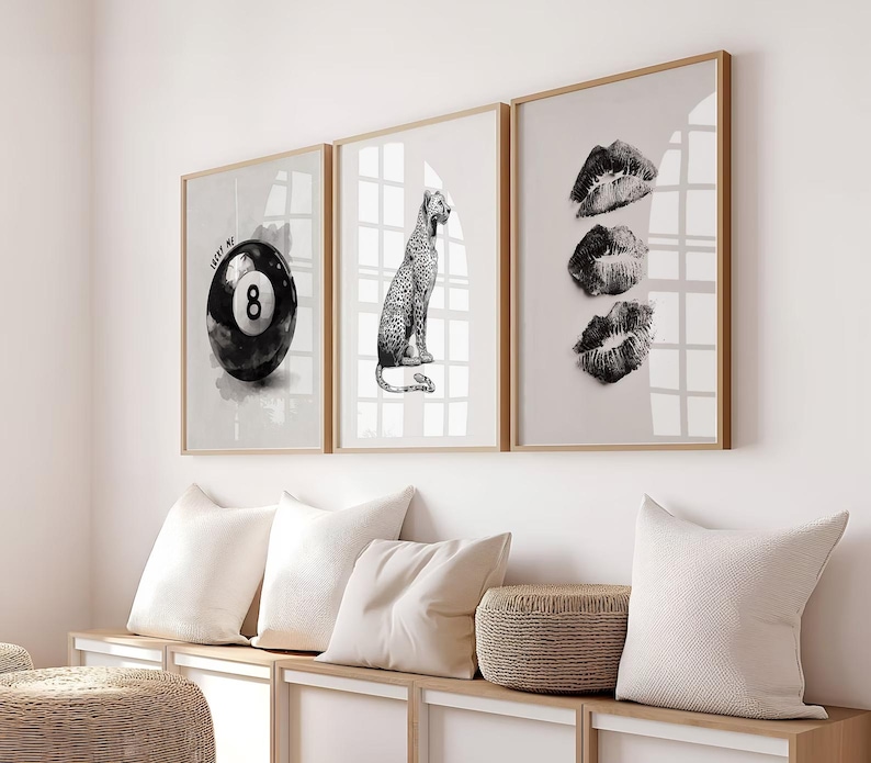 May include: Three framed wall art prints. The first features a black and white 8-ball with the text "ME". The second shows a leopard. The third print displays three lip prints. All are in wooden frames.