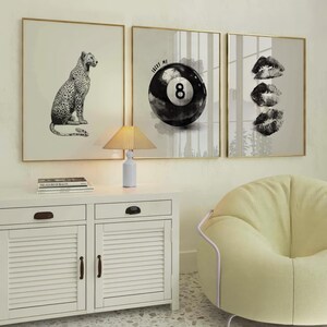 May include: Three framed wall art pieces. The first features a black and white leopard illustration. The second displays an 8-ball with the text "Lucky Me". The third shows three lip prints. All are in gold frames.