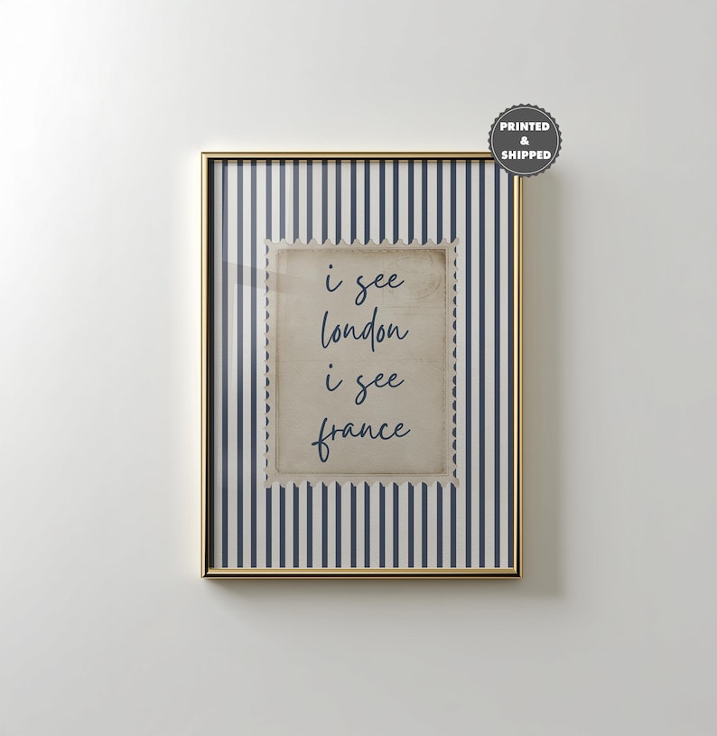 May include: Framed art print with a gold-colored frame. The artwork features a vintage-style postage stamp design with the words "i see london i see france" in a handwritten font. The background has navy blue and white vertical stripes.