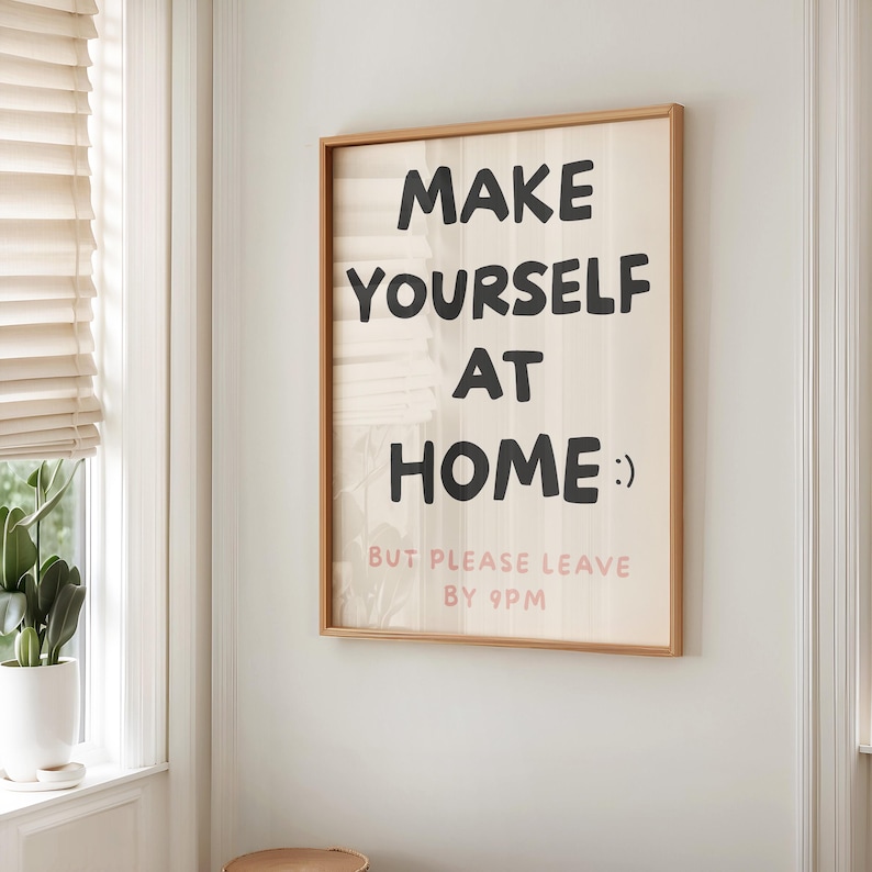 K&ouml;nnte beinhalten: Ein gerahmter Wandkunstdruck mit dem Text "MAKE YOURSELF AT HOME :) BUT PLEASE LEAVE BY 9PM" in Schwarz und Rosa. Der Druck hat einen hellen Holzrahmen und h&auml;ngt an einer wei&szlig;en Wand.