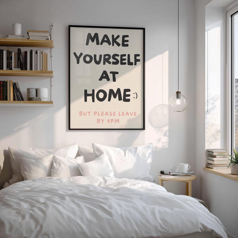 K&ouml;nnte beinhalten: Ein Schlafzimmer mit einem Bett, das mit wei&szlig;er Bettw&auml;sche und Kissen bedeckt ist. Ein gerahmtes Poster an der Wand zeigt den Text "MAKE YOURSELF AT HOME :) BUT PLEASE LEAVE BY 9PM." Ein kleiner Nachttisch aus Holz und eine H&auml;ngeleuchte sind ebenfalls zu sehen.
