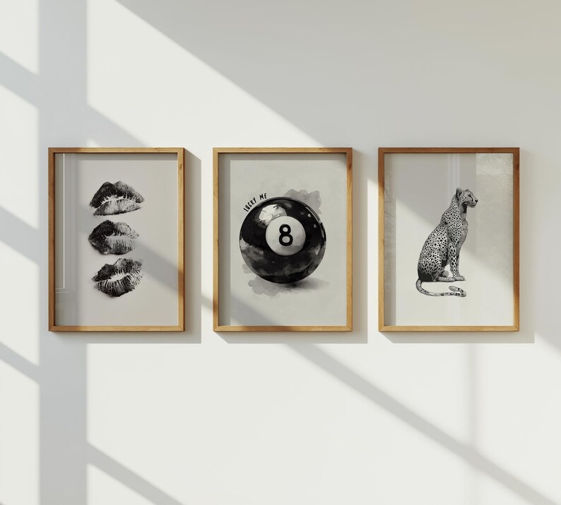 May include: Three framed prints with a neutral background. One print features three sets of black and white lips. Another shows a black and white eight ball with the text "LUCKY ME". The third print is a black and white leopard.