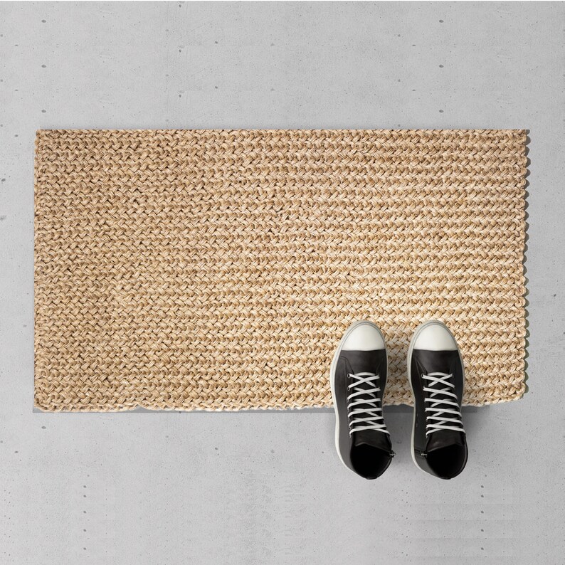 May include: A natural fiber doormat with a woven texture. Two black high-top sneakers with white soles are placed on the mat.