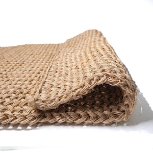 May include: A close-up of a natural fiber doormat, woven in a tight, textured pattern. The mat is rolled up, showcasing the intricate details of the weave.