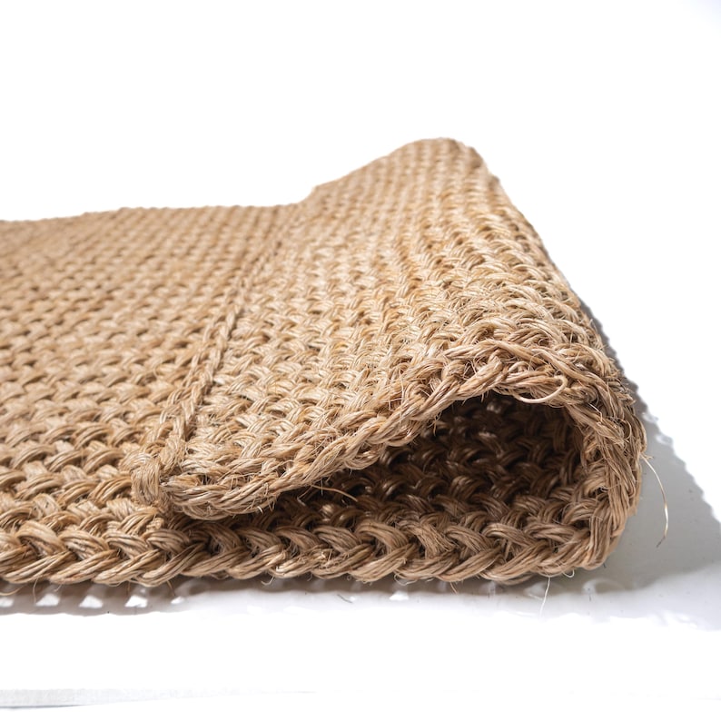 May include: A close-up of a natural fiber doormat, woven in a tight, textured pattern. The mat is rolled up, showcasing the intricate details of the weave.