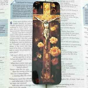 May include: A bookmark featuring a religious image of Jesus Christ on the cross. The image is surrounded by yellow flowers and a wooden frame. The bookmark also includes text from the Bible, including the verse "A good name is better than fine perfume, and the day of death better than the day of birth."