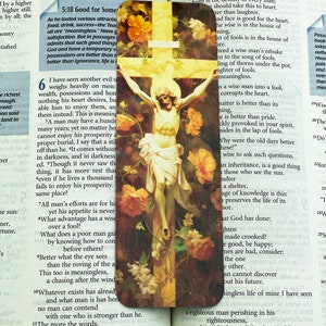 May include: A religious bookmark featuring a cross and a painting of Jesus Christ on the cross. The bookmark is surrounded by flowers and includes text from the Bible, including verses from Ecclesiastes and Proverbs. This bookmark is a lovely way to enhance your Bible study or daily reading.