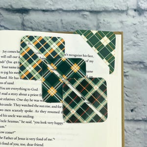 May include: Four green, orange, and white plaid bookmark corners. The bookmarks are made of sturdy cardstock and have a slot for holding a page.