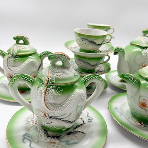 Op de afbeelding: Een groene en witte porseleinen theeset met een drakenontwerp. De set bevat een theepot, roomkan, suikerpot, vier kopjes en vier schoteltjes.