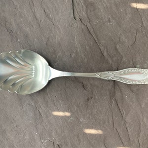 May include: A silver sugar spoon with a scalloped bowl and an ornate handle.