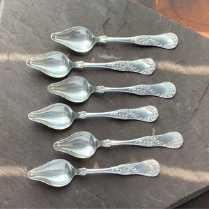 Puede incluir: Juego de seis cucharas de plata con mangos adornados. Las cucharas tienen un cuenco puntiagudo en forma de lágrima.