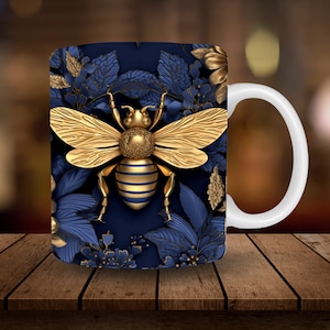 May include: A white ceramic mug with a blue and gold design. The design features a stylized golden bee with wings and a blue and gold floral pattern.