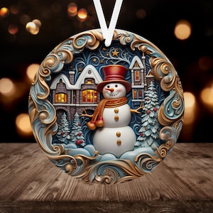 May include: A round Christmas ornament featuring a snowman standing in front of a snow-covered house with lit windows. The ornament has a gold and blue background with intricate details.