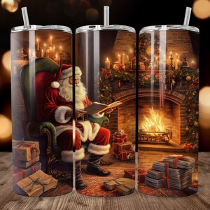 May include: A stainless steel tumbler featuring a festive Christmas scene. Santa Claus is seated in a chair, reading a book in front of a fireplace. The design includes lit candles, wrapped gifts, and a cozy holiday atmosphere.
