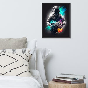 Puede incluir: Una ilustración en blanco y negro de un astronauta con casco y sosteniendo un mando de videojuego. El astronauta está rodeado de salpicaduras de pintura de colores.