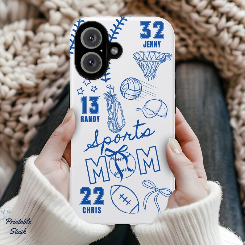 May include: White phone case with blue sports-themed illustrations, including a baseball, basketball net, golf bag, volleyball, and football. The words "Sports Mom" are featured, along with the names and numbers "32 Jenny", "13 Randy", and "22 Chris".