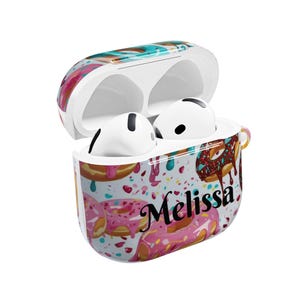 May include: White AirPods Pro case with a colorful donut pattern and the name "Melissa" in black script. The case is open, revealing the white earbuds inside. The design features pink, brown, and blue donuts with sprinkles.
