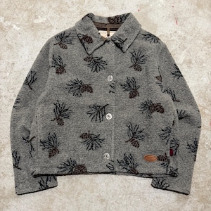 May include: A grey button-up jacket featuring a repeating pattern of dark brown pine cones and pine needles. The jacket has a standard collar, long sleeves, and a small brown oval brand patch on the lower right side. The front closure has four buttons.