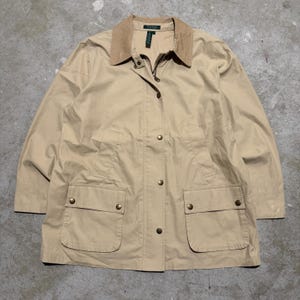 May include: A tan jacket featuring a contrasting light brown corduroy collar, a full-length front zipper, and a snap-button placket. The garment includes two large front patch pockets with snap-button flaps and a Lauren brand label at the neck.