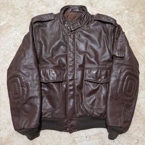 Könnte beinhalten: Ein Set aus drei Keramikbechern mit gesprenkelter, matter Oberfläche. Die Becher sind in Creme-, Hellgrau- und Dunkelgrautönen gehalten. Jeder Becher hat ein schlichtes, minimalistisches Design.