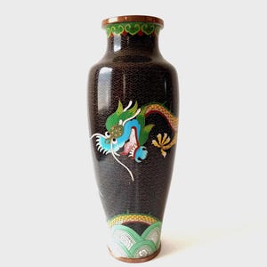 Peut inclure: Un vase cloisonné noir et haut avec un motif de dragon détaillé. Le dragon présente des accents verts, bleus et jaunes sur un fond sombre. Le vase a une surface à motifs et un bord décoratif.