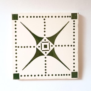 Puede incluir: Azulejo cuadrado blanco roto con un diseño geométrico. El diseño presenta una forma de diamante central con un cuadrado más pequeño en el interior, rodeado de cuatro formas curvas. Acentos verde oscuro y pequeños puntos completan el patrón. Las esquinas tienen cuadrados verde oscuro.