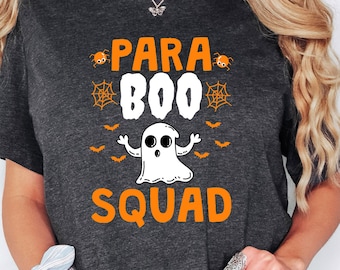 May include: Dark gray t-shirt with the text "Para Boo Squad" in orange and white. The design includes a ghost, bats, and spiderwebs, perfect for Halloween.